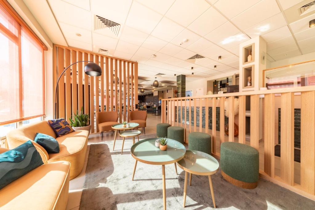 a lobby with a couch and tables and chairs at Mandarina Hotel Luxembourg Airport in Luxembourg