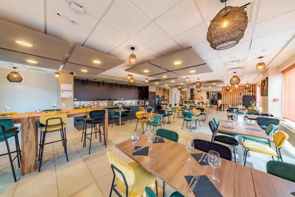 a restaurant with wooden tables and green chairs at Mandarina Hotel Luxembourg Airport in Luxembourg