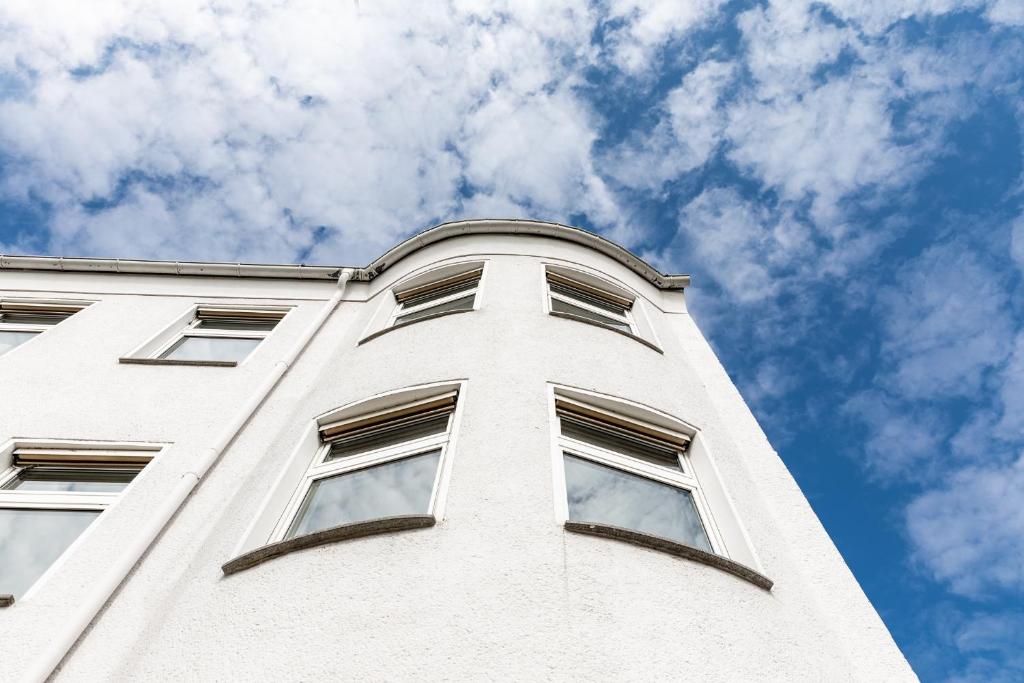 un edificio alto y blanco con ventanas contra un cielo azul en Clubhostel Dessau en Dessau