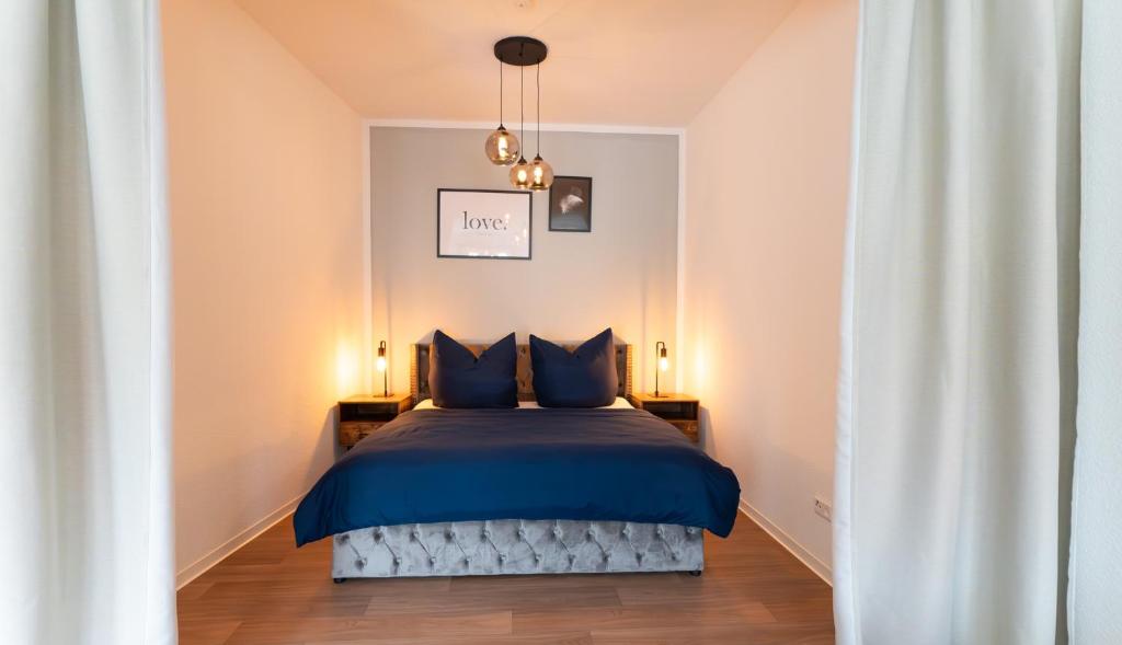 a bedroom with a bed with blue sheets and two lamps at Barrierefrei I free parking I Terasse I Netflix in Quedlinburg