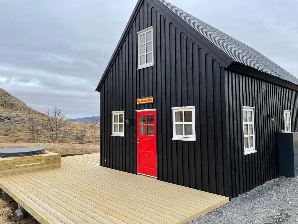 una casa negra con una puerta roja y una terraza en Jóhannshús- tradational Icelandic house, en Hrepphólar