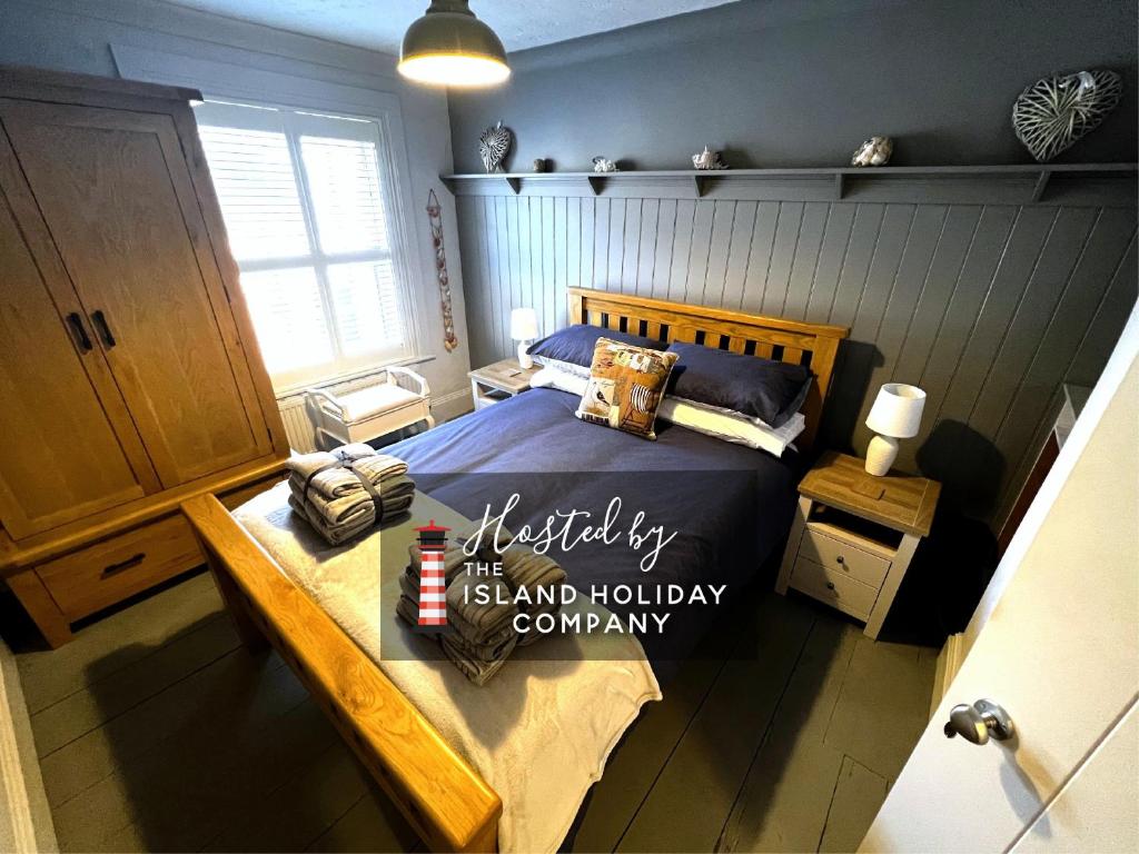 a bedroom with a bed with a sign on it at Ivy Cottage in Brading