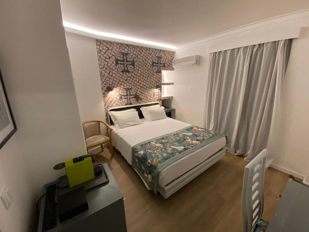 a small bedroom with a bed and a desk at Hotel Cavaleiros De Cristo in Tomar
