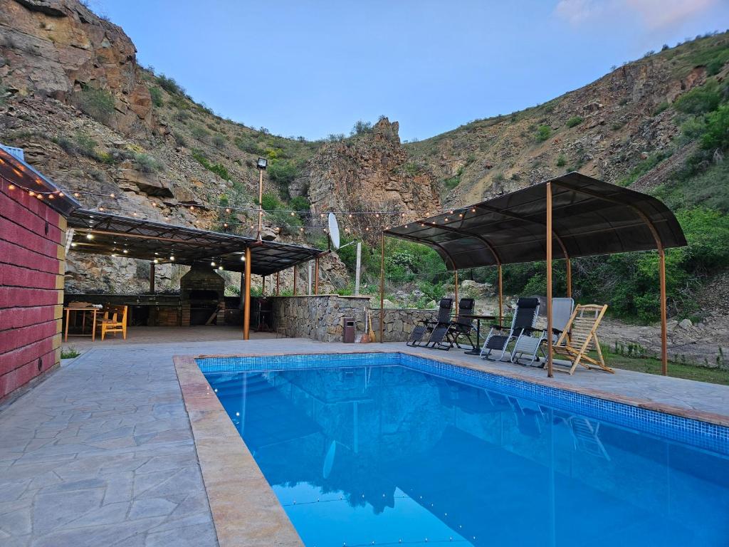 a swimming pool with chairs and umbrellas next to a mountain at Phoenix Villa in Zarritʼapʼ