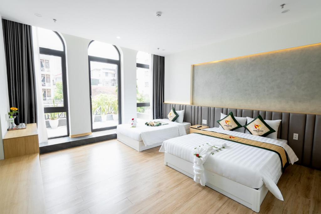 una grande camera con due letti e finestre di TRẠNG NGUYÊN HUẾ HOTEL a Hue