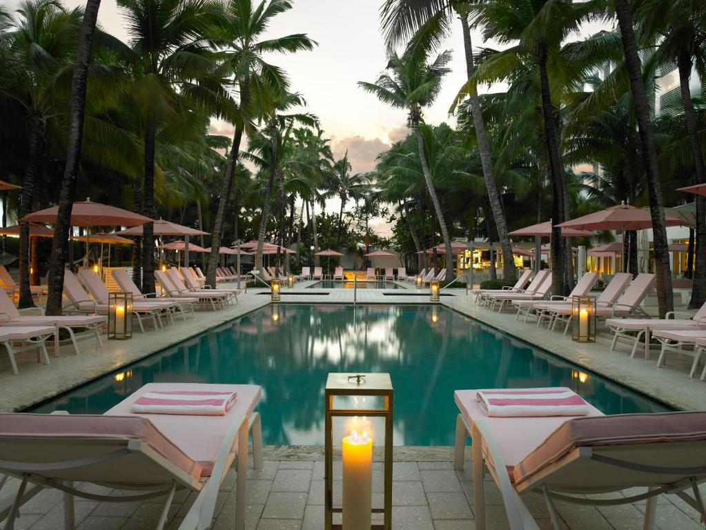 einen Pool mit Liegestühlen und eine Kerze in einem Resort in der Unterkunft Grand Beach Hotel in Miami Beach