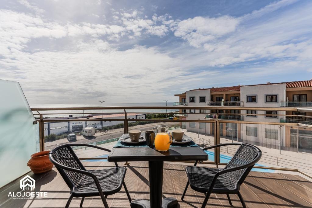 a table and chairs on a balcony with a view at Ocean Paradise - Apartment with ocean view in Ericeira