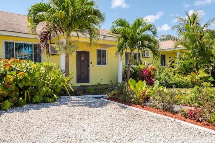 uma casa amarela com palmeiras num jardim em Tropicabana em Nassau