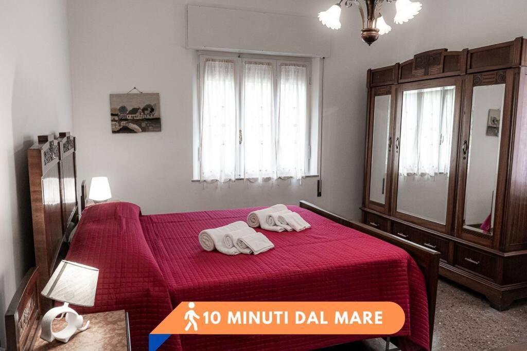 1 dormitorio con 2 toallas en una cama roja en La casa dei fiori 10 min dal mare, en Fano