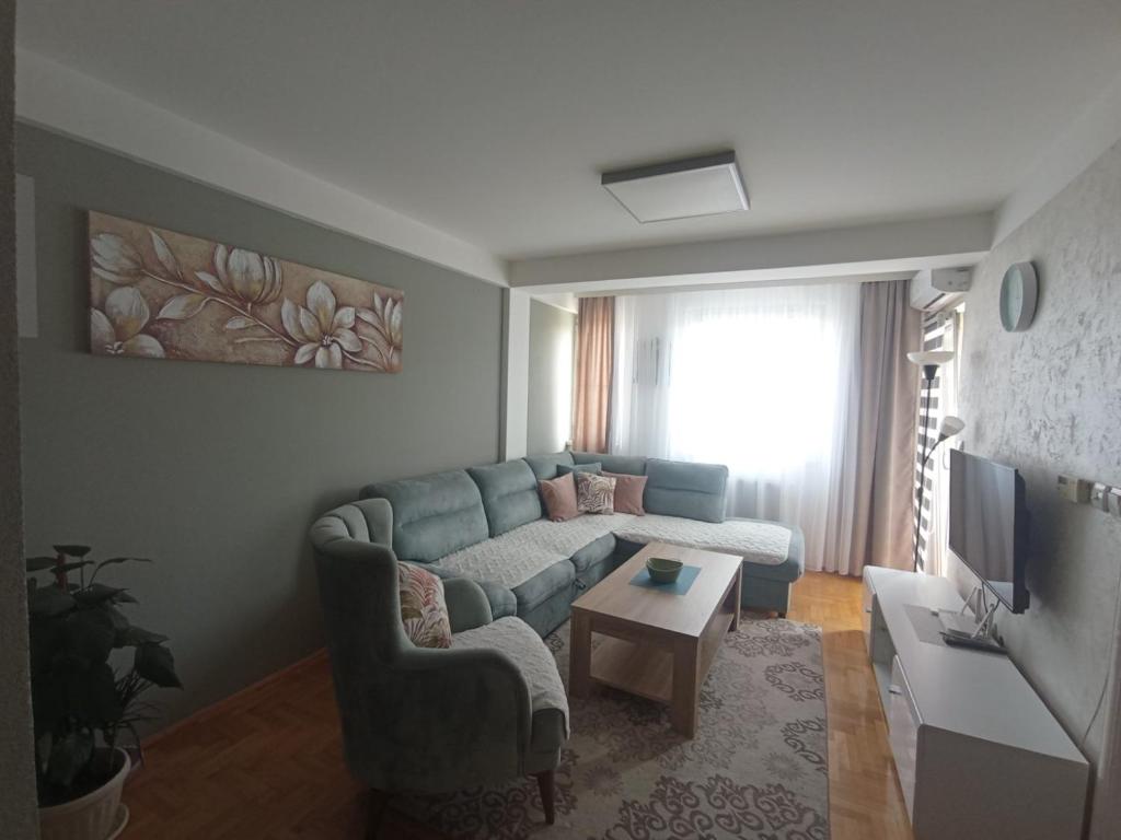 sala de estar con sofá azul y TV en Apartman Dragon Kg en Kragujevac