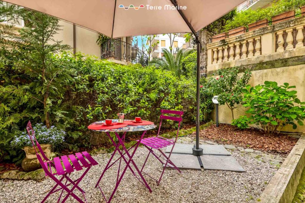 stół z fioletowymi krzesłami i parasolem w obiekcie Élite, Terre Marine w mieście La Spezia