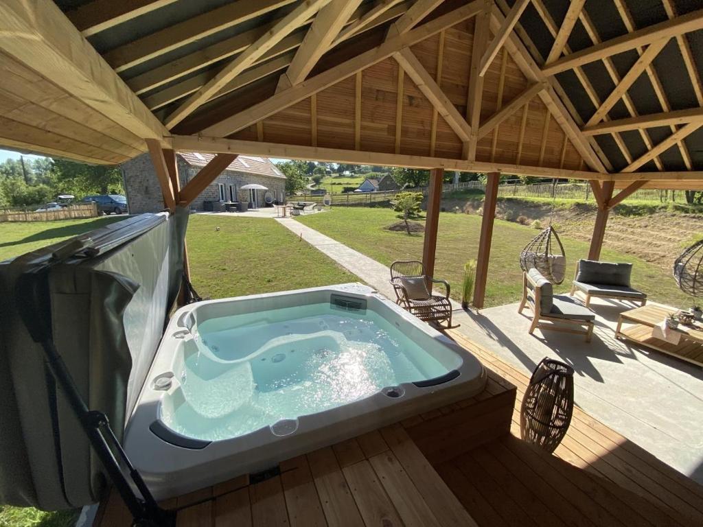 a hot tub on a deck with a roof at Chaignonnières Roulotte 19pers jacuzzi 15min mer in La Chaise-Beaudouin