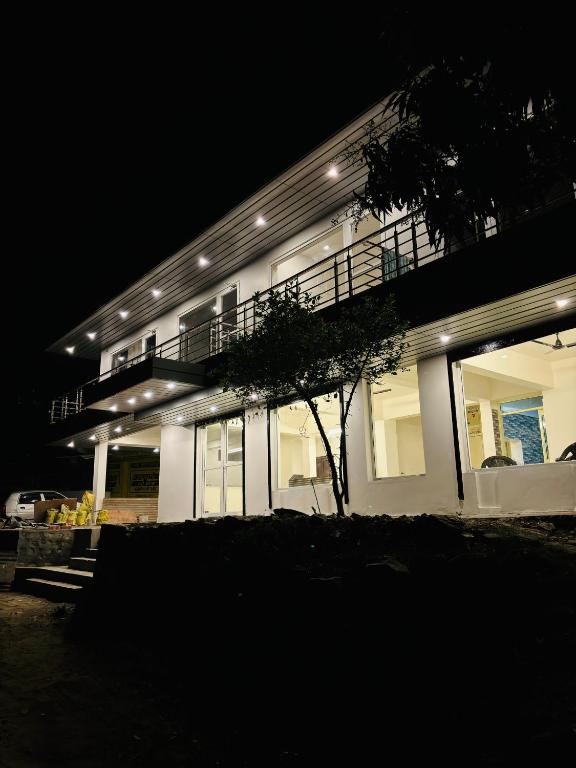 a large white building with a balcony at night at Hotel Kalyani in Nandaprayāg