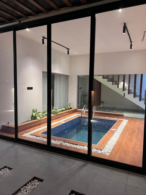 an indoor swimming pool in a house with glass windows at شالية رواء كبلز in á¸¨arÄdÄ«