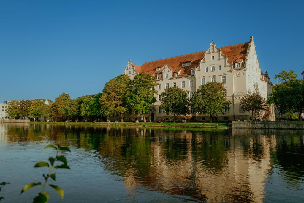 a large white building next to a river at Hotel Amalia - Boutique Hotel in Landshut