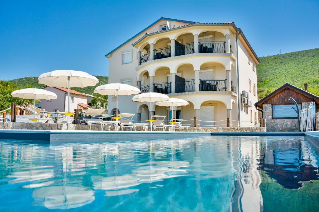 een groot gebouw met een zwembad met parasols bij Sea view in Sveti Juraj