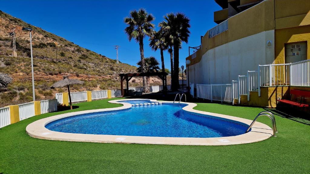 a swimming pool in the middle of a lawn with a building at Cabo de Palos Apartment in Cabo de Palos