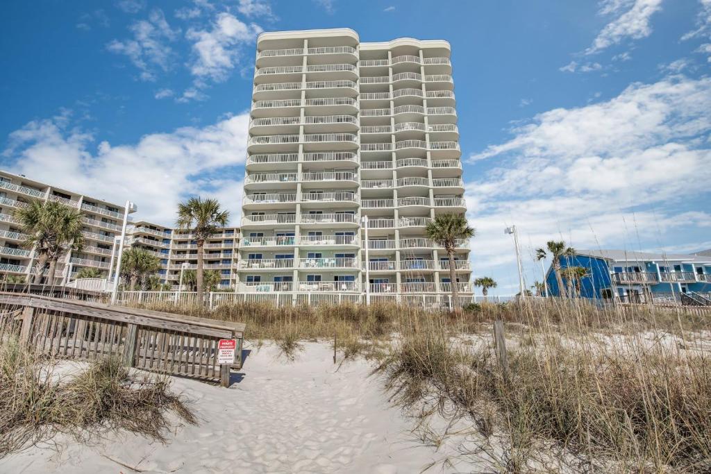 a tall apartment building on the beach with a sandy beach at Tradewinds 001 by Vacation Homes Collection in Orange Beach