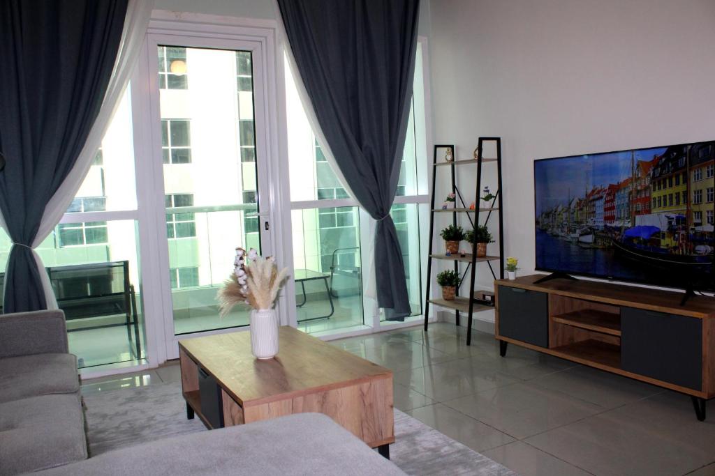een woonkamer met een televisie en een vaas met bloemen bij Skyline Haven In Dubai Marina in Dubai