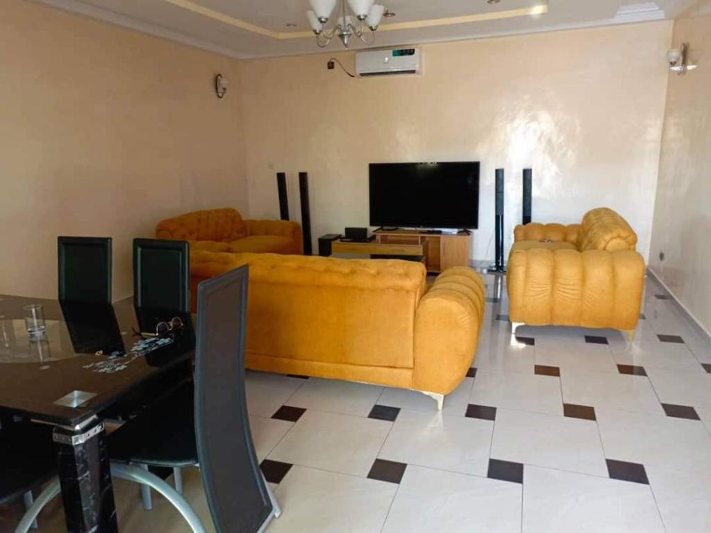 a living room with yellow furniture and a flat screen tv at RÉSIDENCE ABZ ABOMEY in Abomey