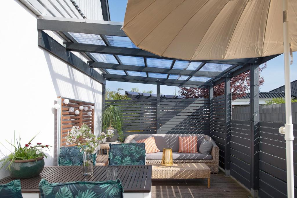 eine Terrasse mit einer Couch und einem Sonnenschirm in der Unterkunft Ferienwohnung 'alte Schule' in Nienhagen