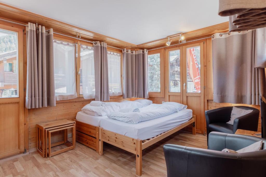 um quarto com uma cama, uma cadeira e janelas em Studio dans le plus beau village de Suisse em Grimentz