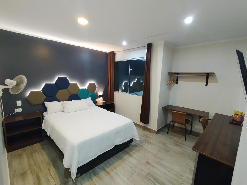 a bedroom with a white bed and a desk and a desk at Hospedaje Diamantes in Huacho
