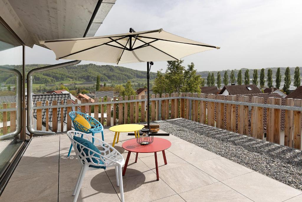 a patio with a table and chairs and an umbrella at Architektenhaus c5 mit Seesicht in Öhningen