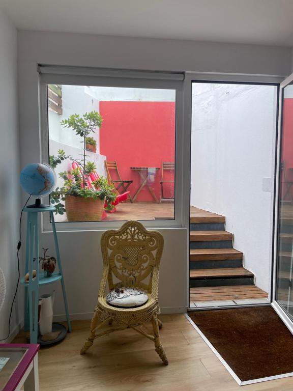 a living room with a chair and a staircase at Casinha Azul in Horta