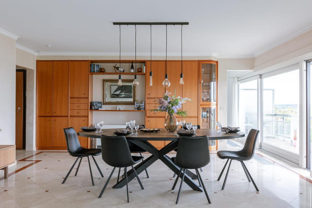 een eetkamer met een grote tafel en stoelen bij Huswell - Apartment with lake view & common indoor pool in Knokke-Heist