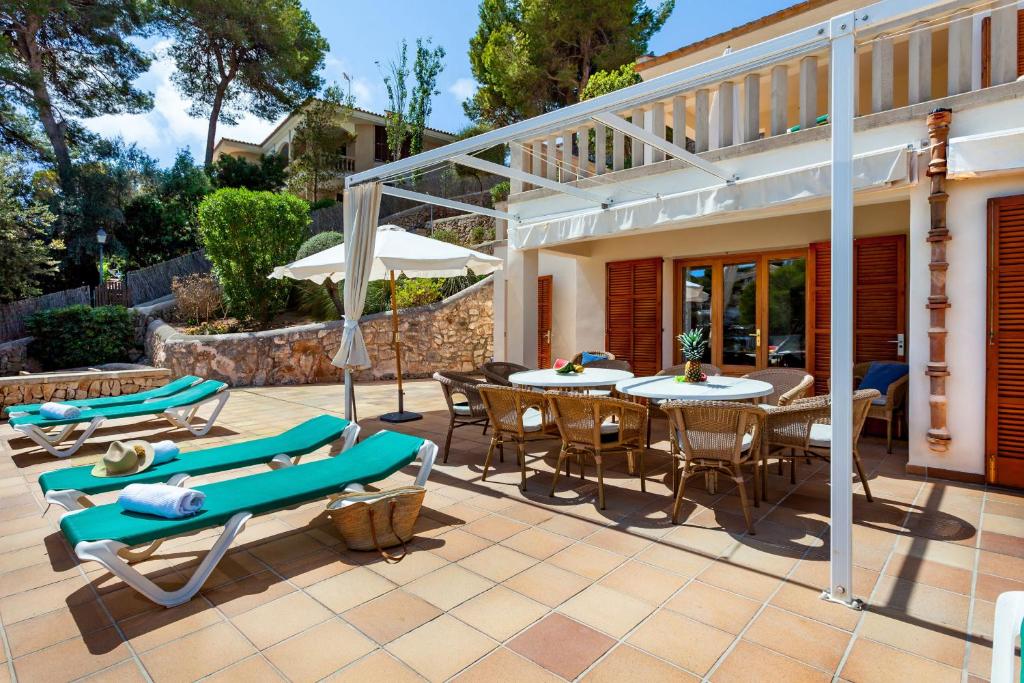 a patio with a table and chairs and umbrellas at Sa Trona Beach House in Cala Santanyi