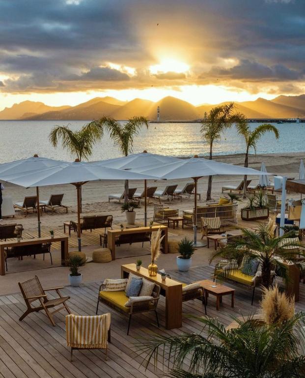 a beach with tables and umbrellas on a beach at Five Seas by Inwood Hotels in Cannes