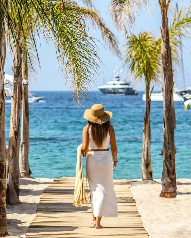 a woman in a hat walking on a wooden path by the ocean at Five Seas by Inwood Hotels in Cannes