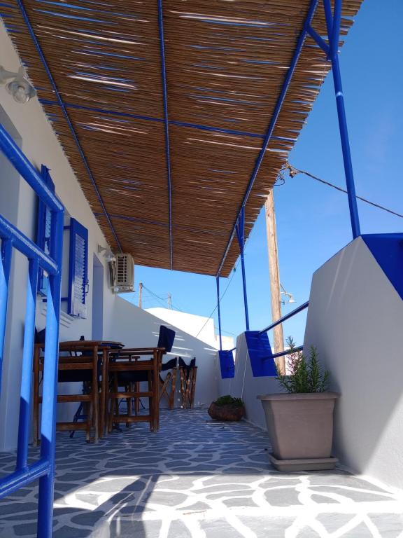 a patio with a wooden roof with a table and chairs at Meltemi Rooms and Studios in Anafi