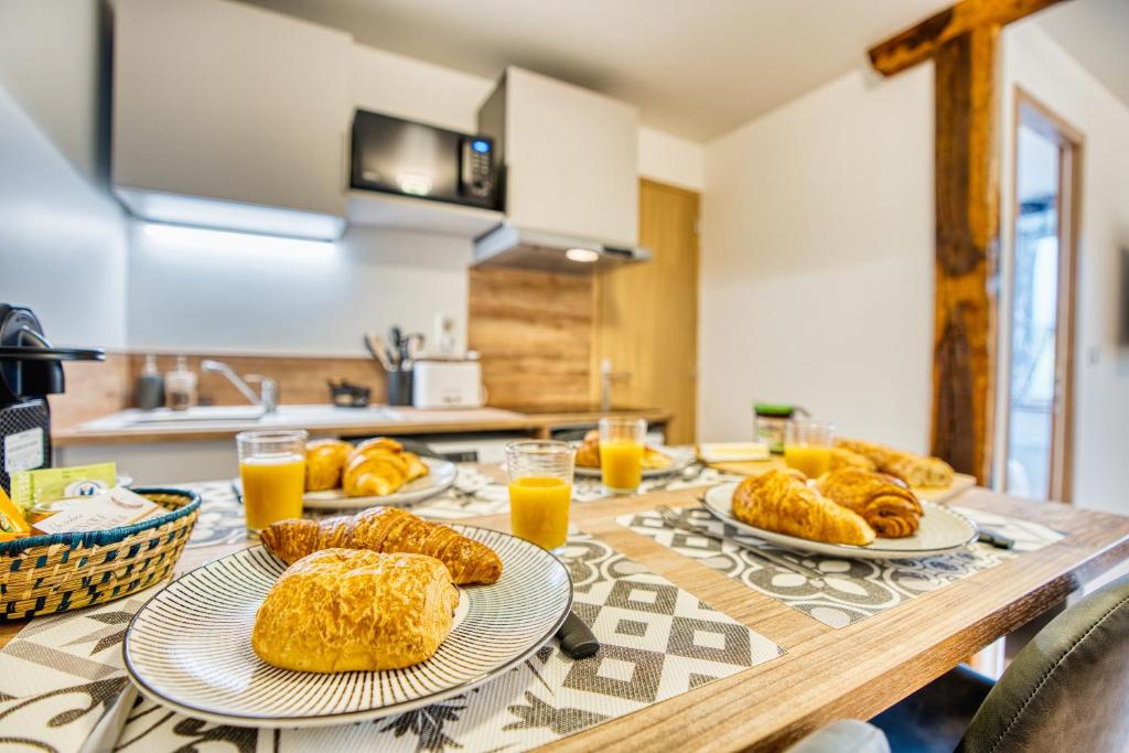 a wooden table with plates of bread and orange juice at Les Hourtous Netflix Wi-Fi Fibre Terasse 4 pers in Banassac