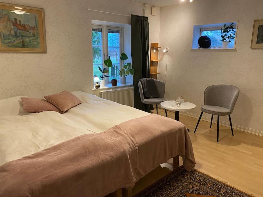 een slaapkamer met een bed en 2 stoelen en een tafel bij Lantgård nära stad, fiske o golf in Malmö