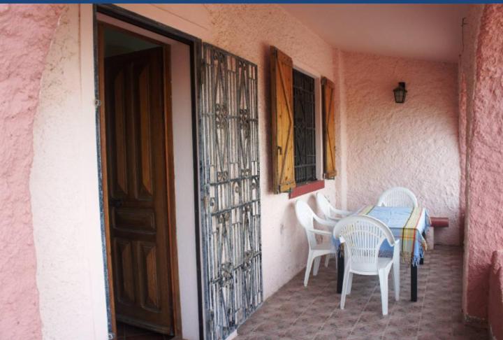 een tafel en stoelen naast een gebouw met een deur bij VILLA CATERINA in Calasetta
