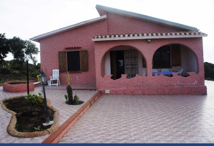 a small pink house with a courtyard in front of it at VILLA CATERINA in Calasetta