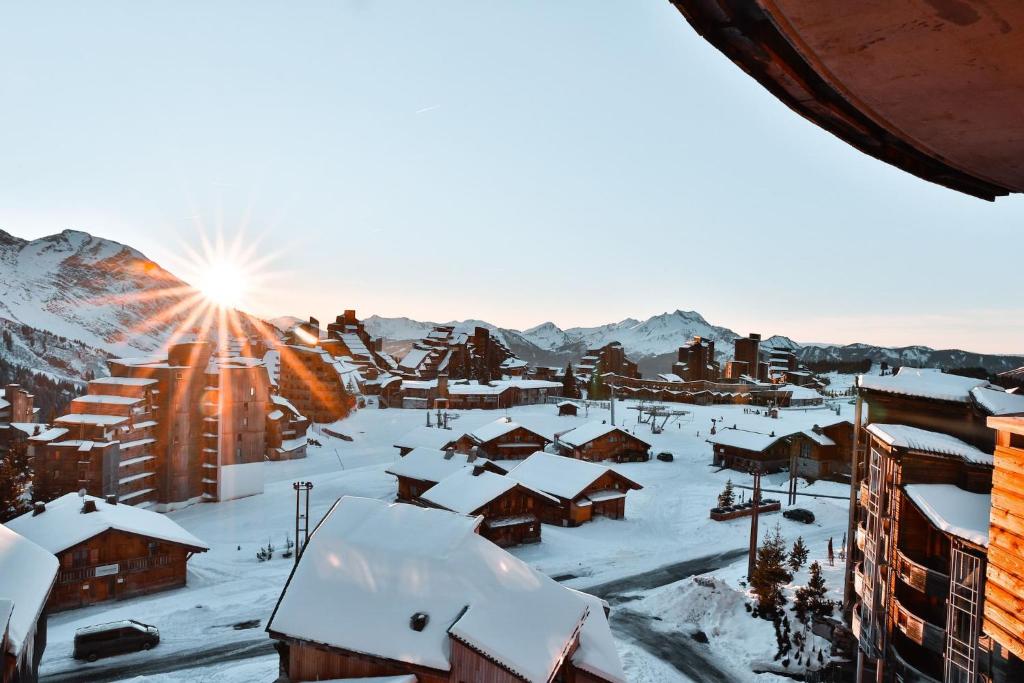 a village covered in snow with the sun in the background at IMMODREAMS - L'Igloo - Avoriaz in Avoriaz