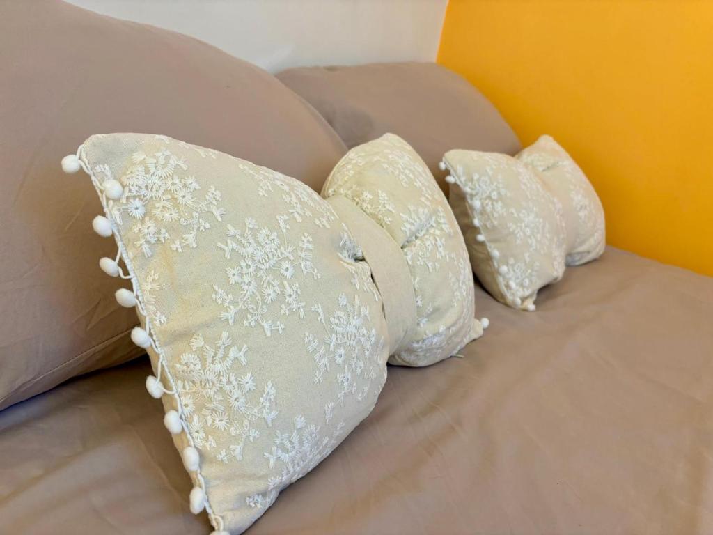 four white pillows on a couch with a yellow wall at Appartement Cosy sur la Prestigieuse rue Faidherbe, à deux pas de la gare Lille Flandre in Lille