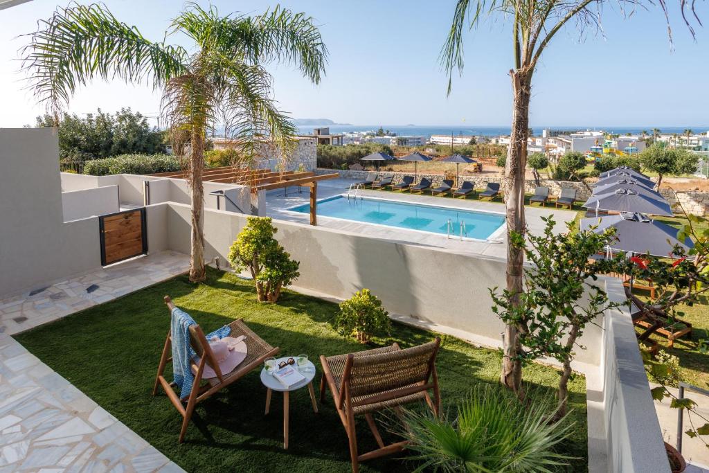 uma imagem de um quintal com uma piscina e palmeiras em Basilico Suites Adults Only em Gouves