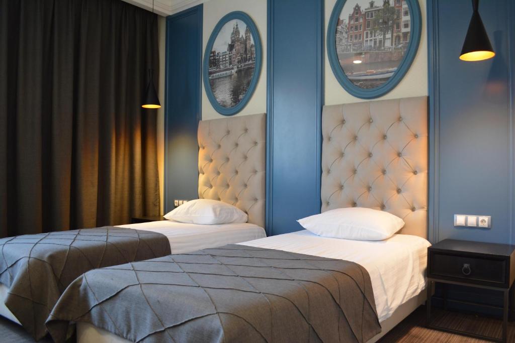 2 Betten in einem Zimmer mit blauen Wänden und Spiegeln in der Unterkunft Hotel Rafael Готель Рафаель in Lwiw