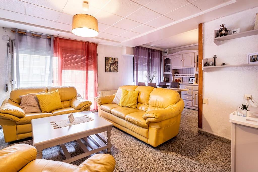 a living room with yellow couches and a kitchen at Precioso apartamento con terraza en Valencia in Valencia