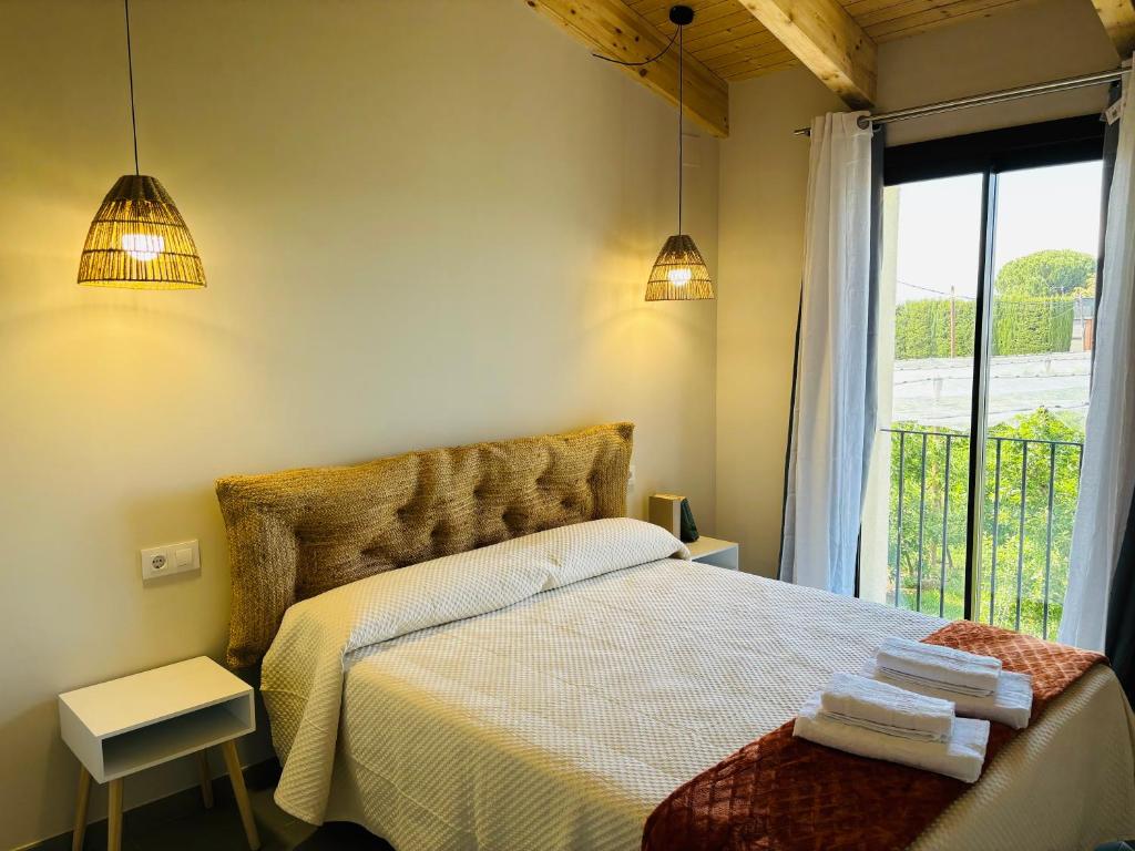 a bedroom with a bed with a window and two lights at Can Mas in Sant Pere Pescador