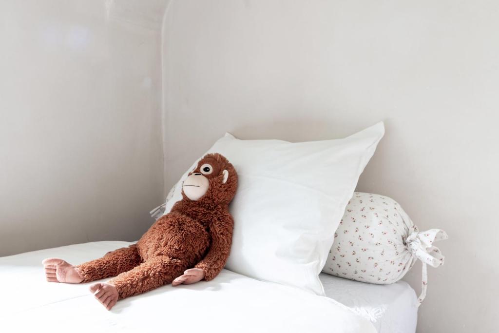 a stuffed monkey sitting on a bed next to a pillow at Bed end breakfast du centre in Bourg-Saint-Maurice