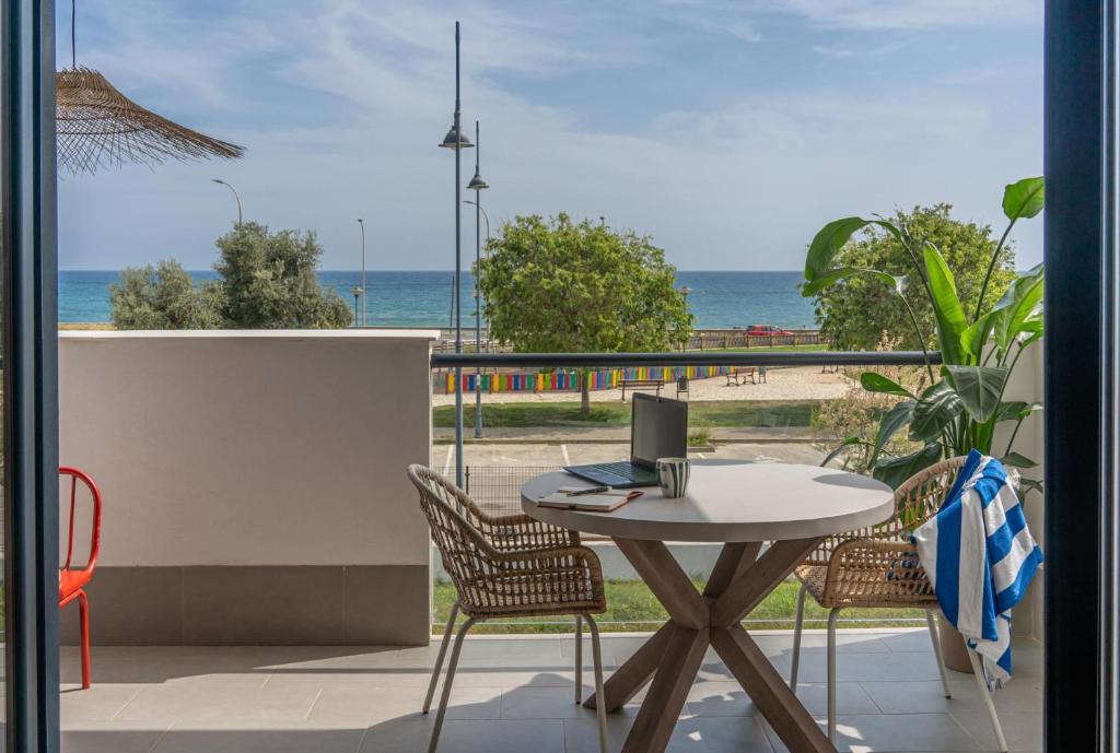 einen Tisch und Stühle mit einem Laptop auf dem Balkon mit Strandblick in der Unterkunft Heima in front of the Sea in Málaga