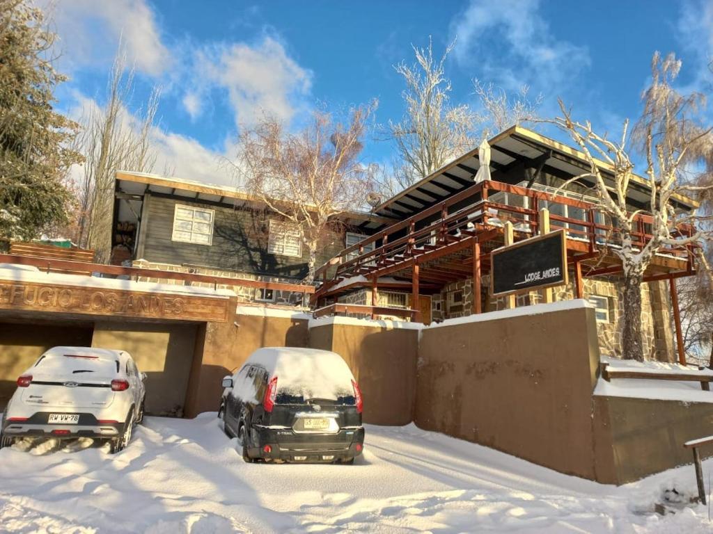 dos autos estacionados en la nieve frente a una casa en Lodge Andes, en Farellones