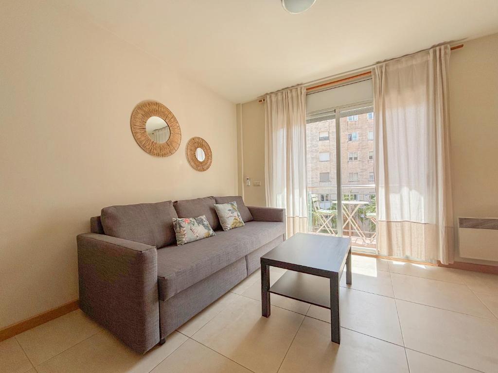 uma sala de estar com um sofá, uma mesa e uma janela em Clauhomes Reus Centro em Reus