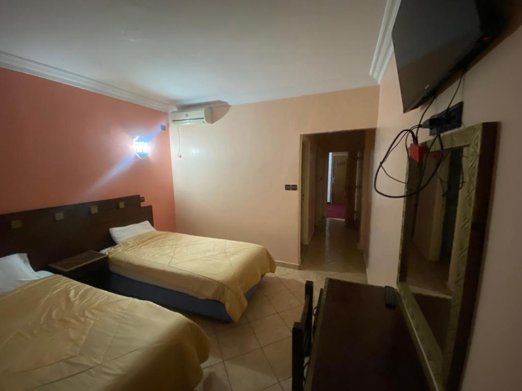 a hotel room with two beds and a television at Merry Hôtel in Agadir