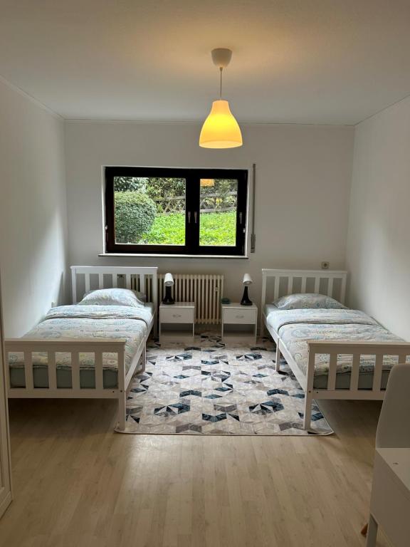 Dieses weiße Zimmer verfügt über 2 Betten und ein Fenster. in der Unterkunft Ferienwohnung Mittenaar in Mittenaar